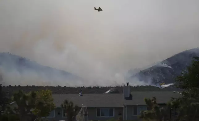 The Bridge Fire sends a plume of smoke over properties Wednesday, Sept. 11, 2024, in Piñon Hills in San Bernardino County, Calif. (AP Photo/Eric Thayer)