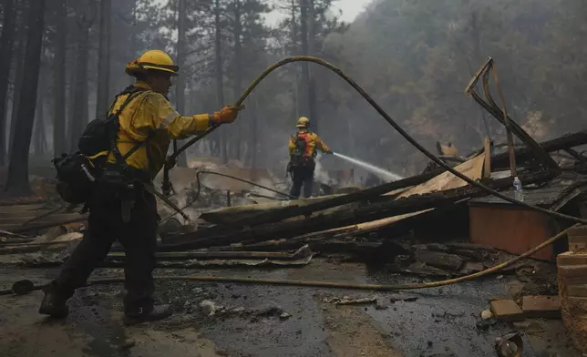 Firefighters hose down hot spots on a fire-ravaged property while battling the Bridge Fire Wednesday, Sept. 11, 2024, in Wrightwood, Calif. (AP Photo/Eric Thayer)