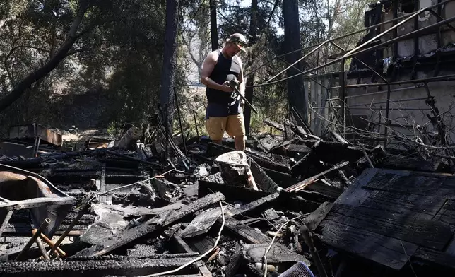 Matt Howe sifts through his partially damaged property after the Airport Fire swept through Thursday, Sept. 12, 2024, in El Cariso Village, in unincorporated Riverside County, Calif. (AP Photo/Gregory Bull)