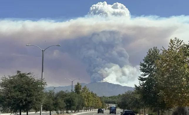 A plum of smoke created by the Airport Fire rises over a mountain top Tuesday, Sept. 10, 2024, in a view from Irvine, Calif. (AP Photo/Eugene Garcia)