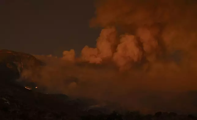 Smoke from the Airport Fire billows over a mountain as the sun sets Monday, Sept. 9, 2024, near Trabuco Canyon, Calif. (AP Photo/Gregory Bull)