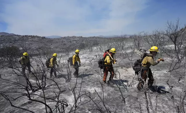 Members of Riverside County Cal Fire walk up a hillside while battling the Airport Fire Wednesday, Sept. 11, 2024, in El Cariso Village, in unincorporated Riverside, County, Calif. (AP Photo/Gregory Bull)