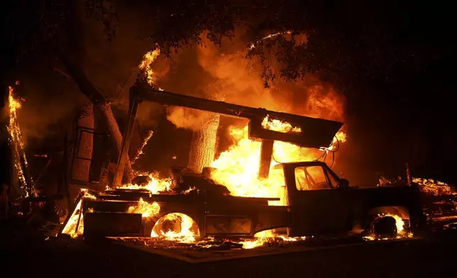 A vehicle burns from the Airport Fire Tuesday, Sept. 10, 2024, in El Cariso, an unincorporated community in Riverside County, Calif. (AP Photo/Eric Thayer)