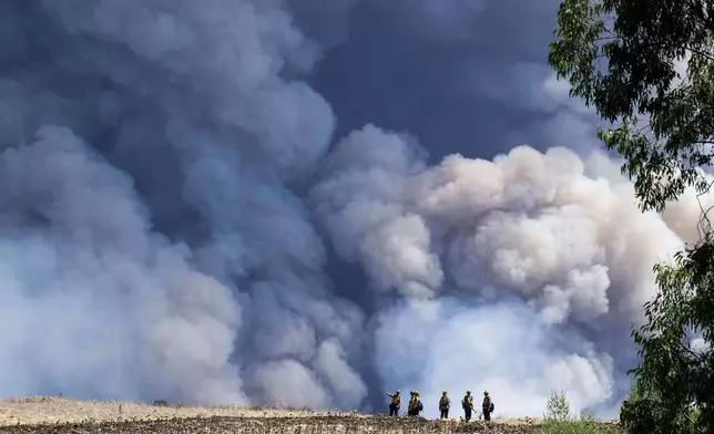 Firefighters monitor the Airport Fire from a ridge near Porter Ranch in Trabuco Canyon, Calif., Tuesday, Sept. 10, 2024. (Paul Bersebach/The Orange County Register via AP)