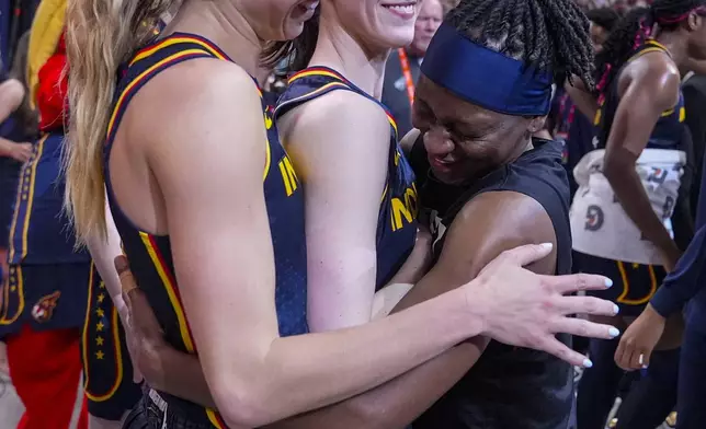 Indiana Fever guard Caitlin Clark, center is hugged by Lexie Hull, left, and Erica Wheeler (17) after a WNBA basketball game against the Dallas Wings in Indianapolis, Sunday, Sept. 15, 2024. (AP Photo/Michael Conroy)