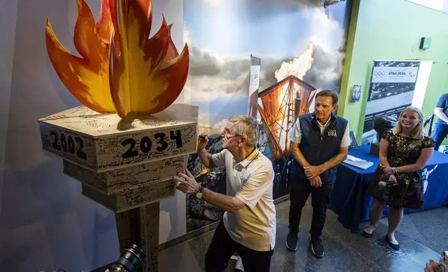 International Olympic Committee President Thomas Bach, center, signs the 2034 torch display at the 2002 Olympic and Paralympic Museum within Utah Olympic Park in Park City, Utah, Saturday, Sept. 28. 2024. (Isaac Hale/The Deseret News via AP)