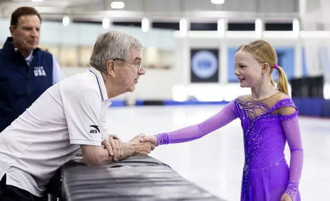 International Olympic Committee President Thomas Bach shakes hands with figure skater Annabelle Atkinson, 10, of Salt Lake City, as they talk at the Utah Olympic Oval in Kearns, Utah, Saturday, Sept. 28. 2024. (Isaac Hale/The Deseret News via AP)