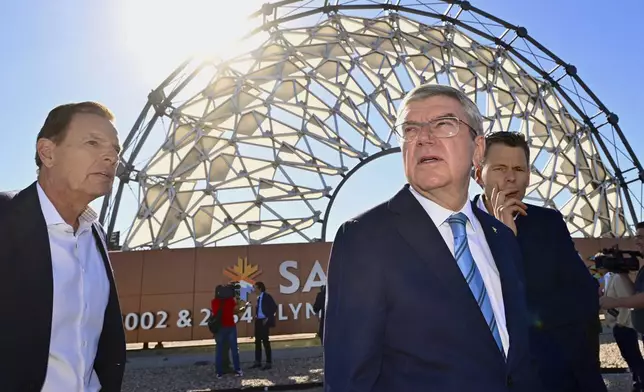 Fraser Bullock, left, the president and CEO of the Salt Lake City-Utah Committee for the Games, joins International Olympic Committee President Thomas Bach, foreground right, near the Hoberman Arch at the Salt Lake City International Airport, as he leads a delegation visiting ahead of the 2034 Winter Olympics, Friday Sept. 27, 2024. (Scott G Winterton/The Deseret News via AP)