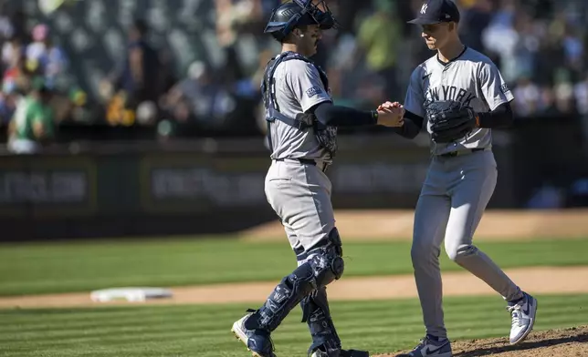 New York Yankees catcher Austin Wells, left, celebrates a win with pitcher Luke Weaver after a baseball game against the Oakland Athletics in Oakland, Calif., Sunday, Sept. 22, 2024. (AP Photo/Nic Coury)