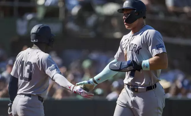 New York Yankees' Jazz Chisholm Jr. (13) celebrates with Aaron Judge (right) after he scored during the seventh inning of a baseball game against the Oakland Athletics in Oakland, Calif., Sunday, Sept. 22, 2024. (AP Photo/Nic Coury)