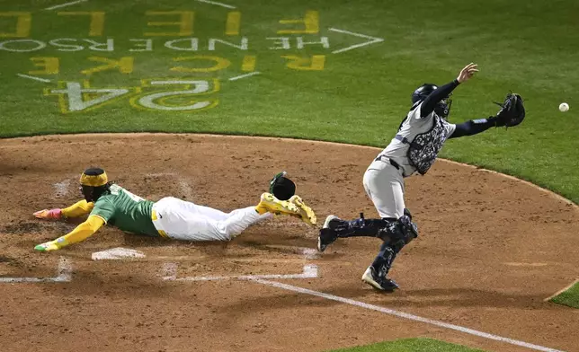 Oakland Athletics' Lawrence Butler (4) scores against New York Yankees catcher Austin Wells, right, during the fourth inning of a baseball game Friday, Sept. 20, 2024, in Oakland, Calif. (AP Photo/Eakin Howard)