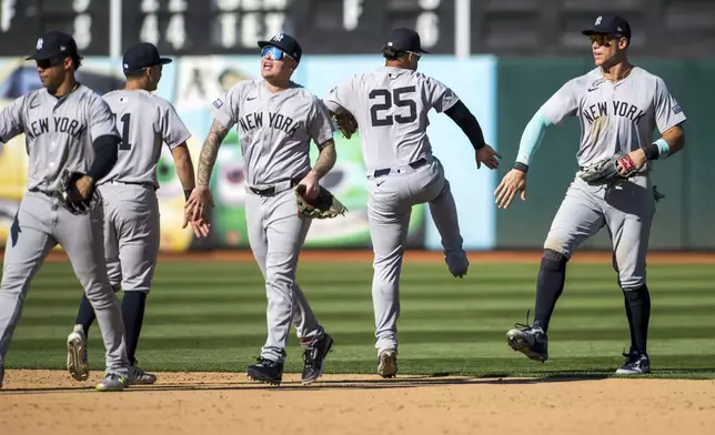 New York Yankees outfielder Aaron Judge, far right, celebrates a win with second baseman Gleyber Torres (25) after a baseball game against the Oakland Athletics in Oakland, Calif., Sunday, Sept. 22, 2024. (AP Photo/Nic Coury)