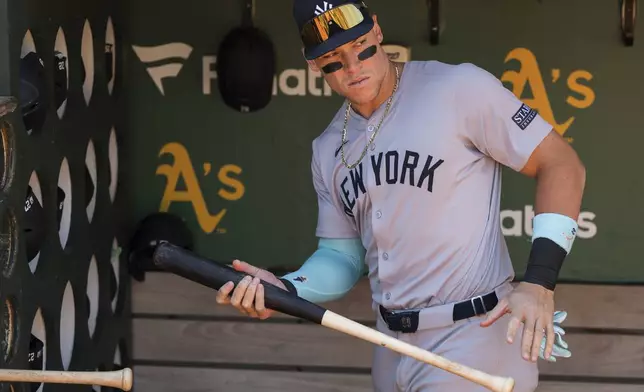 New York Yankees' Aaron Judge grabs a bat from the dugout before a baseball game against the Oakland Athletics in Oakland, Calif., Sunday, Sept. 22, 2024. (AP Photo/Nic Coury)