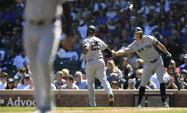 New York Yankees' Giancarlo Stanton, right, celebrates with teammate Gleyber Torres (25) after Torres scored on an Austin Wells ground out during the first inning of a baseball game against the Chicago Cubs in Chicago, Saturday, Sept. 7, 2024. (AP Photo/Paul Beaty)