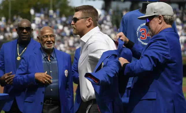 New member of the Chicago Cubs Hall of Fame Kerry Wood, left, gets his jacket from fellow Hall of Fame member Rick Sutcliffe, right before a baseball game between the Chicago Cubs and New York Yankees in Chicago, Sunday, Sept. 8, 2024. (AP Photo/Paul Beaty)