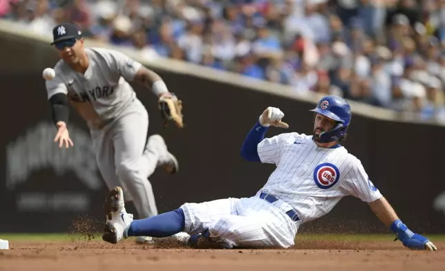 Chicago Cubs' Dansby Swanson, right, slides safely into second as New York Yankees second baseman Gleyber Torres, left, commits a throwing error during the first inning of a baseball game in Chicago, Sunday, Sept. 8, 2024. (AP Photo/Paul Beaty)