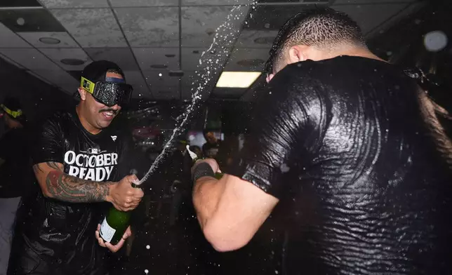 New York Yankees starting pitcher Nestor Cortes, left, sprays champagne on a teammate as they celebrate clinching a playoff spot after a 2-1 win in 10 innings over the Seattle Mariners in a baseball game Wednesday, Sept. 18, 2024, in Seattle. (AP Photo/Lindsey Wasson)