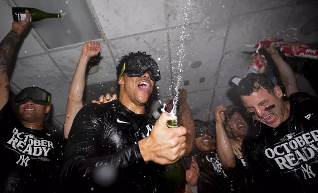 New York Yankees right fielder Juan Soto, center, celebrates clinching a playoff spot with teammates, including first baseman Anthony Rizzo, right, after a 2-1 win in 10 innings over the Seattle Mariners in a baseball game Wednesday, Sept. 18, 2024, in Seattle. (AP Photo/Lindsey Wasson)