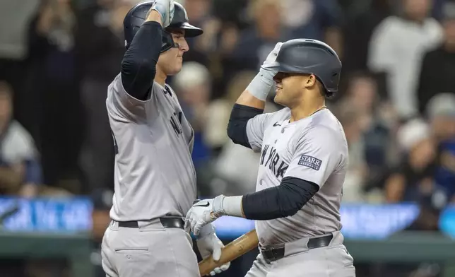 New York Yankees' Jasson Dominguez, right, celebrates with Anthony Rizzo after hitting a solo home run during the fifth inning of a baseball game against the Seattle Mariners, Tuesday, Sept. 17, 2024, in Seattle. (AP Photo/Stephen Brashear)