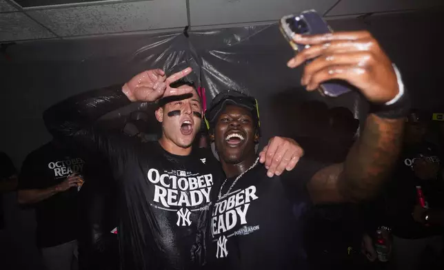 New York Yankees first baseman Anthony Rizzo, left, poses for a photo with third baseman Jazz Chisholm Jr., right, as they celebrate clinching a playoff spot after a 2-1 win in 10 innings over the Seattle Mariners in a baseball game Wednesday, Sept. 18, 2024, in Seattle. (AP Photo/Lindsey Wasson)