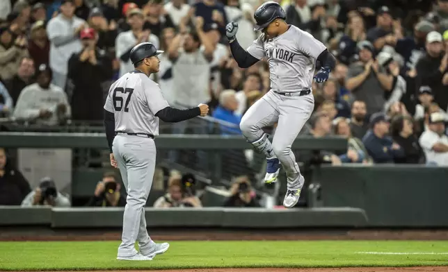 New York Yankees' Juan Soto, right, celebrates with third base coach Luis Rojas after hitting a two-run home run during the fourth inning of a baseball game against the Seattle Mariners, Tuesday, Sept. 17, 2024, in Seattle. (AP Photo/Stephen Brashear)