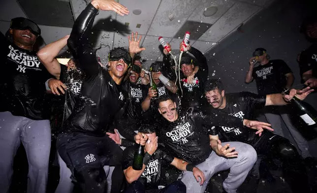 The New York Yankees celebrate clinching a playoff spot after a 2-1 win in 10 innings over the Seattle Mariners in a baseball game Wednesday, Sept. 18, 2024, in Seattle. (AP Photo/Lindsey Wasson)