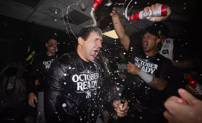 New York Yankees relief pitcher Tommy Kahnle, left, celebrates clinching a playoff spot with teammates after a 2-1 win over the Seattle Mariners in 10 innings in a baseball game Wednesday, Sept. 18, 2024, in Seattle. (AP Photo/Lindsey Wasson)