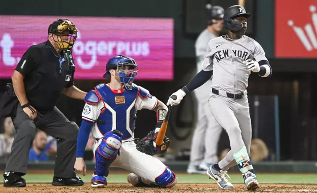 New York Yankees Jazz Chisolm Jr., right, watches his RBI single in the sixth inning as Texas Rangers catcher Jonah Heim, center, and home plate umpire Bruce Dreckman, left, look on during a baseball game, Monday, Sept. 2, 2024, in Arlington, Texas. (AP Photo/Albert Pena)