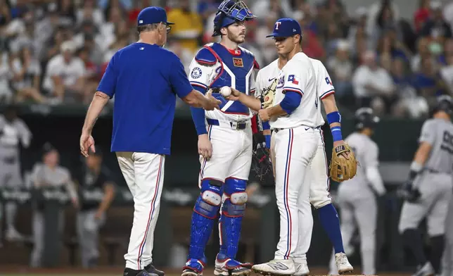 Texas Rangers starting pitcher Jack Leiter, front right, hands the ball to manager Bruce Bochy, left, as catcher Jonah Heim, center, looks on in the sixth inning of a baseball game against the New York Yankees, Monday, Sept. 2, 2024, in Arlington, Texas. (AP Photo/Albert Pena)