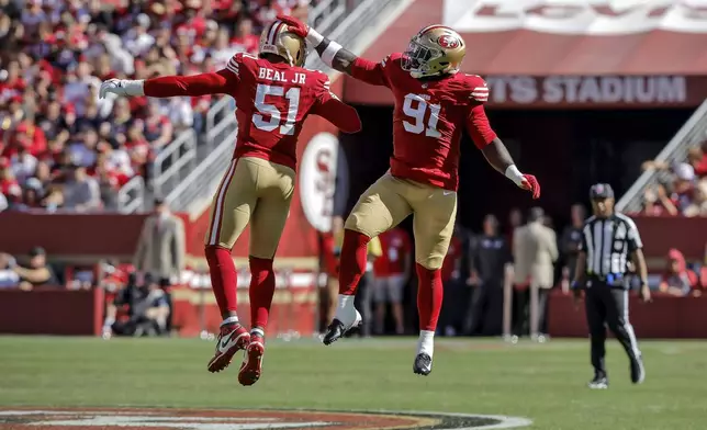 San Francisco 49ers' Robert Beal Jr. (51) and Sam Okuayinonu (91) celebrate after a defensive stop in the second half of an NFL football game against the New England Patriots in Santa Clara, Calif., Sunday, Sept. 29, 2024. (Carlos Avila Gonzalez/San Francisco Chronicle via AP)