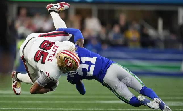 San Francisco 49ers' George Kittle (85) os tacked by Seattle Seahawks' Devon Witherspoon (21) during the first half of an NFL football game, Thursday, Oct. 10, 2024, in Seattle. (AP Photo/Lindsey Wasson)