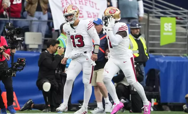 San Francisco 49ers quarterback Brock Purdy (13) ND Deebo Samuel Sr. (1) celebrate a touchdown by Samuel Sr. during the first half of an NFL football game against the Seattle Seahawkse, Thursday, Oct. 10, 2024, in Seattle. (AP Photo/Lindsey Wasson)