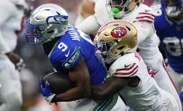 Seattle Seahawks running back Kenneth Walker III (9) is tackled by San Francisco 49ers' Malik Mustapha (6) during the first half of an NFL football game, Thursday, Oct. 10, 2024, in Seattle. (AP Photo/Lindsey Wasson)