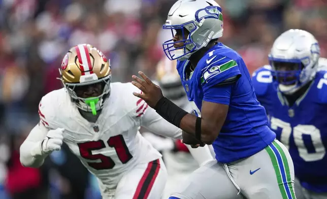 Seattle Seahawks quarterback Geno Smith runs the ball against San Francisco 49ers defensive end Robert Beal Jr. (51) during the first half of an NFL football game Thursday, Oct. 10, 2024 in Seattle. (AP Photo/Lindsey Wasson)