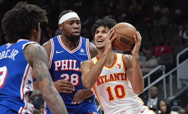 Atlanta Hawks forward Zaccharie Risacher (10) tries to get past Philadelphia 76ers forward Guerschon Yabusele (28) in the first half of a preseason NBA basketball game Monday, Oct. 14, 2024, in Atlanta. (AP Photo/John Bazemore)