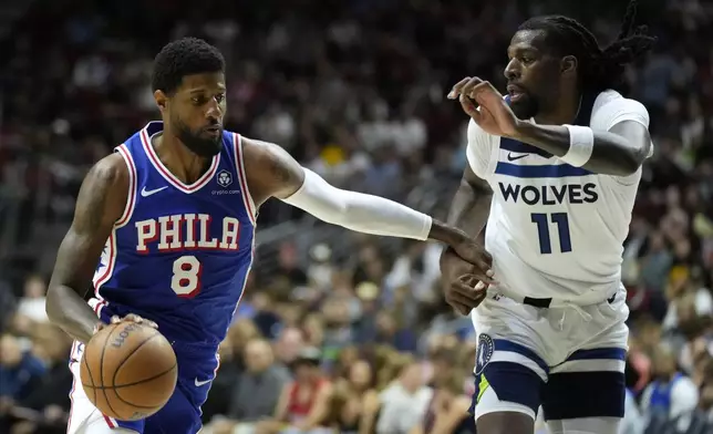 Philadelphia 76ers forward Paul George (8) drives to the basket past Minnesota Timberwolves center Naz Reid (11) during the first half of an NBA preseason basketball game, Friday, Oct. 11, 2024, in Des Moines, Iowa. (AP Photo/Charlie Neibergall)