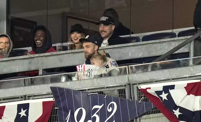 ADDS ID OF MAN AT SECOND LEFT AS JERROD CARMICHAEL - Travis Kelce, top right, and Taylor Swift sit with actor-comedian Jerrod Carmichael, second left, as they watch Game 1 of the baseball AL Championship Series between the Cleveland Guardians and New York Yankees Monday, Oct. 14, 2024, in New York. (AP Photo/Frank Franklin II)