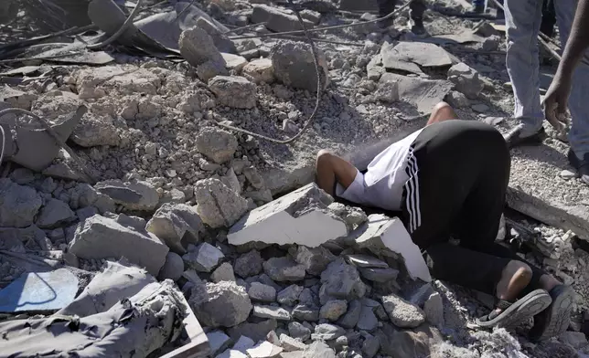 A man searches for a missing relative at the site of Israeli airstrikes that destroyed buildings facing the city's main government hospital in a densely-populated neighborhood, in southern Beirut, Lebanon, Tuesday, Oct. 22, 2024. (AP Photo/Hussein Malla)