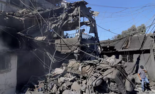 A man, left, checks his damaged house at the site of Israeli airstrikes that destroyed buildings facing the city's main government hospital in a densely-populated neighborhood, in southern Beirut, Lebanon, Tuesday, Oct. 22, 2024. (AP Photo/Hussein Malla)