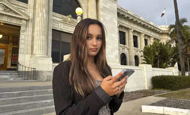 Kaylin Hayman, 17, scrolls on her phone outside Ventura City Hall in Ventura, Calif., Oct. 17, 2024. (AP Photo/Eugene Garcia)