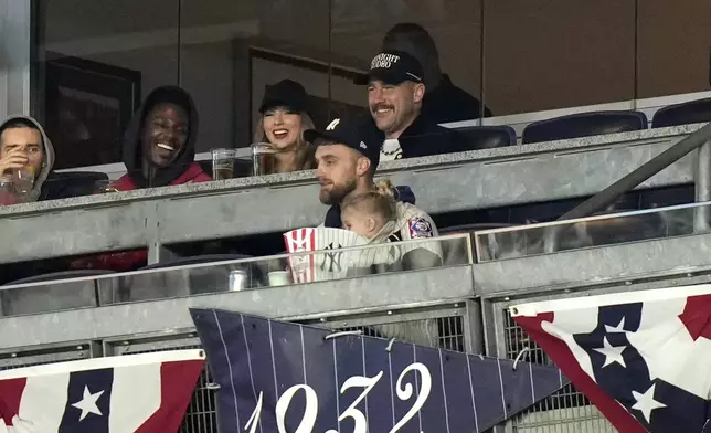 Travis Kelce, top right, and Taylor Swift watch Game 1 of the baseball AL Championship Series between the Cleveland Guardians and New York Yankees Monday, Oct. 14, 2024, in New York. (AP Photo/Frank Franklin II)