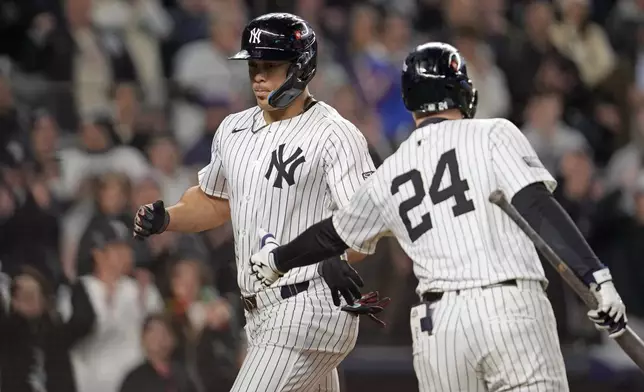 New York Yankees' Juan Soto, left, celebrates with Alex Verdugo (24) after scoring on a wild pitch against the Cleveland Guardians during the third inning in Game 1 of the baseball AL Championship Series Monday, Oct. 14, 2024, in New York. (AP Photo/Godofredo Vásquez)