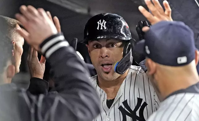 New York Yankees' Giancarlo Stanton celebrates in the dugout after hitting a home run against the Cleveland Guardians during the seventh inning in Game 1 of the baseball AL Championship Series Monday, Oct. 14, 2024, in New York. (AP Photo/Godofredo Vásquez )