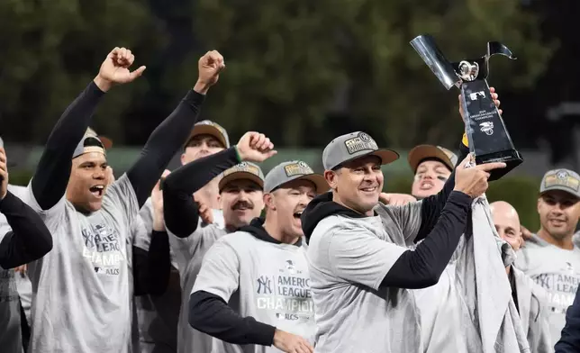 New York Yankees manager Aaron Boone holds up the American League Championship trophy after Game 5 of the baseball AL Championship Series against the Cleveland Guardians Sunday, Oct. 20, 2024, in Cleveland. The Yankees won 5-2 to advance to the World Series. (AP Photo/Sue Ogrocki)