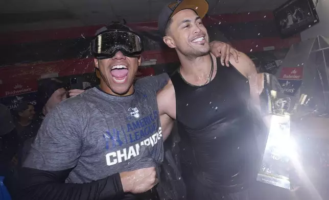 New York Yankees' Juan Soto, left, and Giancarlo Stanton celebrate after Game 5 of the baseball AL Championship Series against the Cleveland Guardians Sunday, Oct. 20, 2024, in Cleveland. The Yankees won 5-2 to advance to the World Series. (AP Photo/Godofredo A. Vásquez )