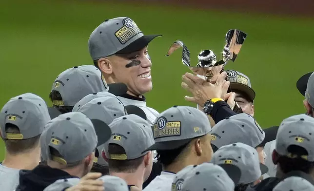 New York Yankees' Aaron Judge holds the American League Championship trophy after Game 5 of the baseball AL Championship Series against the Cleveland Guardians Sunday, Oct. 20, 2024, in Cleveland. The Yankees won 5-2 to advance to the World Series. (AP Photo/Jeff Roberson)