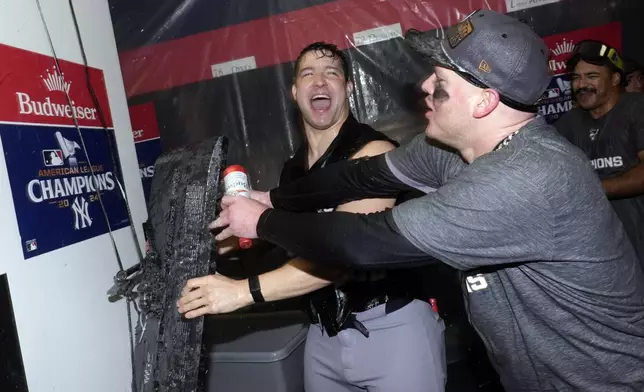 New York Yankees' Tommy Kahnle, left, and Alex Verdugo celebrate in clubhouse after Game 5 of the baseball AL Championship Series against the Cleveland Guardians Sunday, Oct. 20, 2024, in Cleveland. The Yankees won 5-2 to advance to the World Series. (AP Photo/Godofredo A. Vásquez )