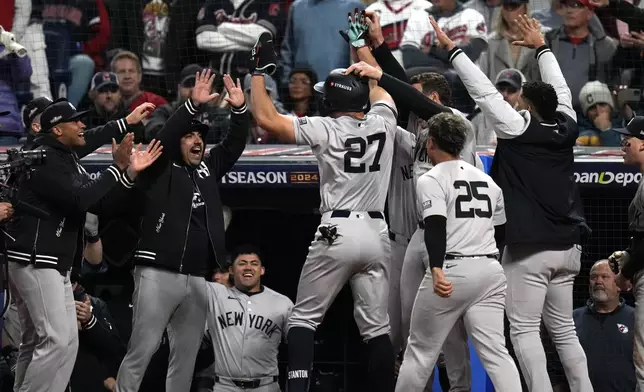 New York Yankees' Giancarlo Stanton (27) celebrates with teammates after hitting a home run against the Cleveland Guardians during the eighth inning in Game 3 of the baseball AL Championship Series Thursday, Oct. 17, 2024, in Cleveland.(AP Photo/Jeff Roberson)