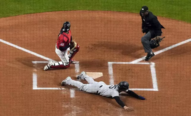 New York Yankees' Gleyber Torres (25) slides across home plate after being tagge out by Cleveland Guardians catcher Bo Naylor during the first inning in Game 5 of the baseball AL Championship Series Saturday, Oct. 19, 2024, in Cleveland. (AP Photo/Godofredo A. Vásquez )