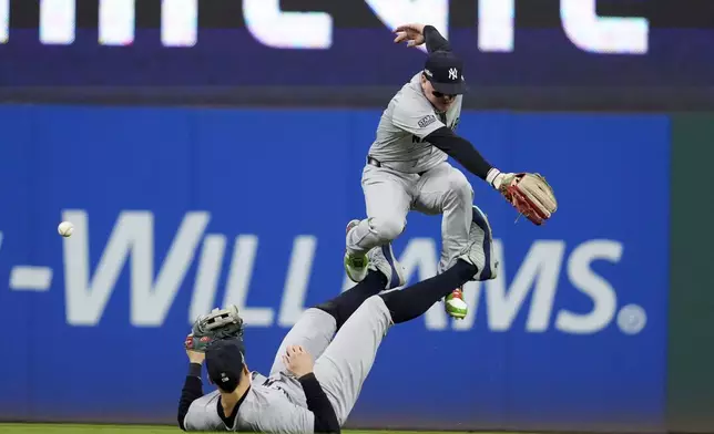 New York Yankees center fielder Aaron Judge, bottom, tries to catch a single by Cleveland Guardians' David Fry as left fielder Alex Verdugo leaps over him during the fifth inning in Game 5 of the baseball AL Championship Series Saturday, Oct. 19, 2024, in Cleveland. (AP Photo/Godofredo A. Vásquez)